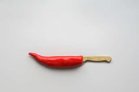 Red hot pepper in the shape of a knife on a gray background with a copy space.の写真素材