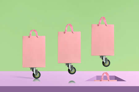 Creative layout or sale concept. Shopping bags on wheels jumping in the hole.の写真素材