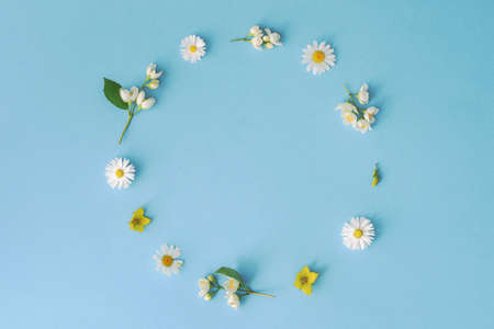 Floral composition in the form of a wreath of flowers on a blue background. Spring or summer layout of flowers with a copy of the space.の写真素材