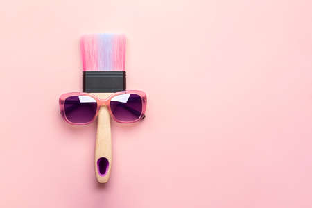 Paintbrush in sunshine safety glasses on pink background with copy space. creative concept.の写真素材