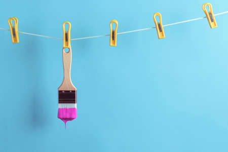 Paintbrush soiled in purple paint hanging from a clothesline. Creative renovation concept.の写真素材