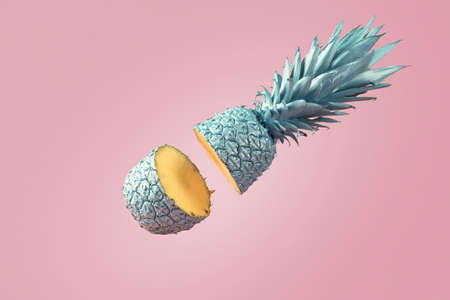 creative food concept. Blue cut pineapple falls on a pink background.の写真素材