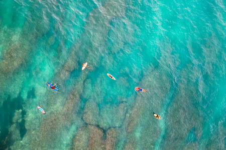 Aerial view of surfers in the ocean against a backdrop of turquoise seabed.の写真素材