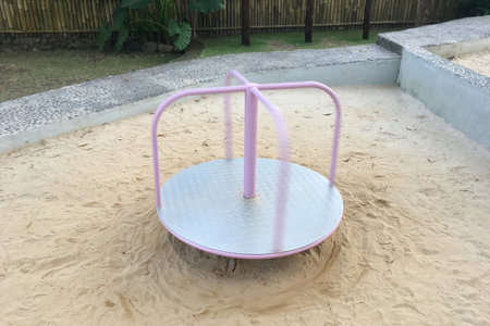 Children's pink carousel spins without people on the playground.の写真素材