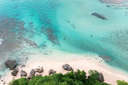 Aerial views of rocky and sandy beach and turquoise ocean at low tide.の写真素材