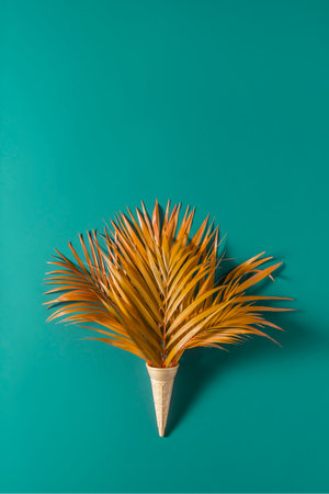 Creative summer or autumn concept. Palm leaves in a waffle cone on a blue background.の写真素材