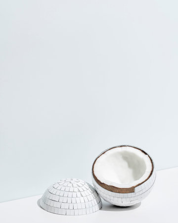 White mirror ball cut in two with coconut inside on white background.