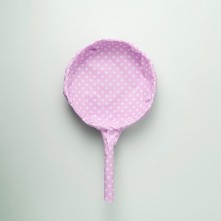 Frying pan packaged in pink polka dot gift paper on a blue pastel background. Creative concept for a woman's gift.の写真素材