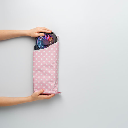 Creative gift concept. Children's hands take the gifted graphic card, wrapped in pink gift paper on a blue background. Top view.の写真素材