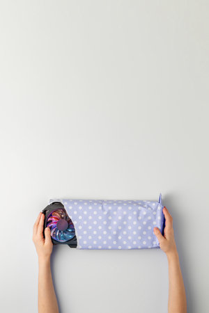 Creative gift concept. Children's hands pick up a gifted graphic card wrapped in blue gift paper on a blue background. Top view.の写真素材