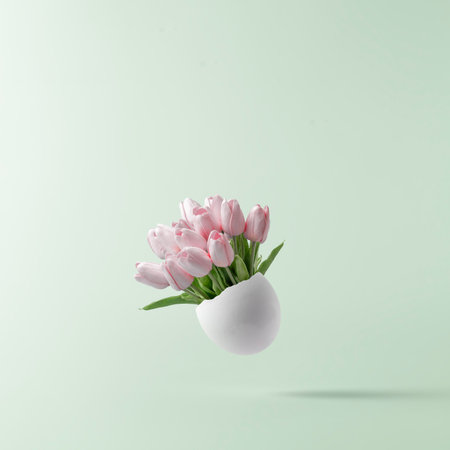 Easter Concept. Bouquet of pink tulips in broken white egg on blue pastel background.の写真素材