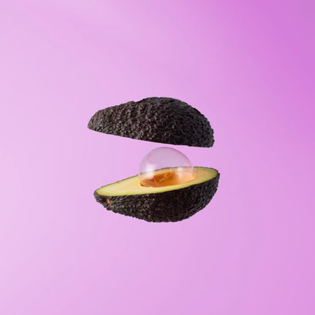 Creative minimalist diet concept. Levitation of an avocado cut in half with an air bubble on a pink background.の写真素材
