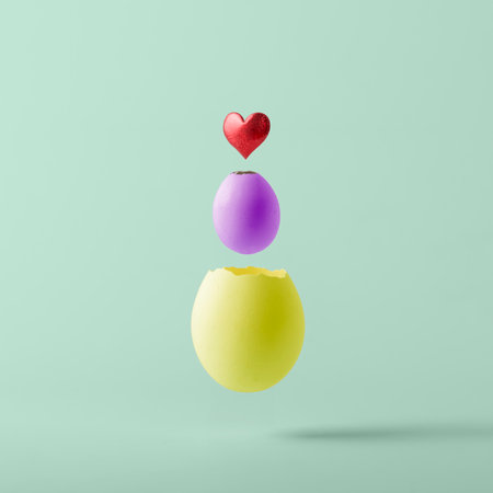 Creative Easter concept. Multicolored Easter eggs flying out of each other with a heart on a green pastel background.の写真素材