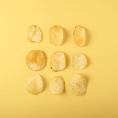 Potato chips on yellow background, top view, flat lay.