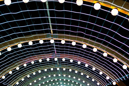 Arches of glowing garlands on a net with neon lines, creating a festive background against the dark skyの写真素材