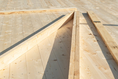 Angled wooden beams laid on the floor of a frame house under constructionの写真素材