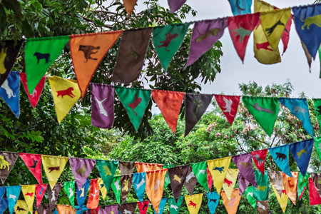 Bright flags with colorful animal silhouettes waving in the wind against lush green foliageの写真素材