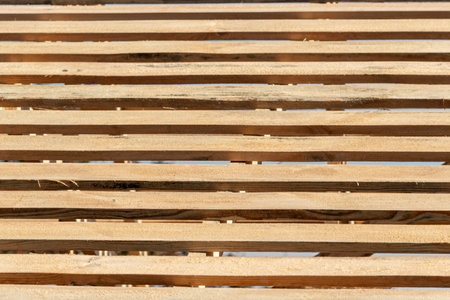 Rows of wooden roof sheathing beams with gaps revealing blue skyの写真素材