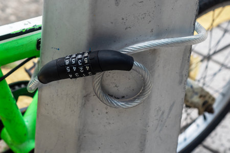A combination lock secures a bicycle to a metal post, emphasizing urban security and theft preventionの写真素材