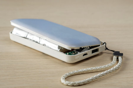 A damaged portable power bank with a swollen battery and partially open casing. The device shows...