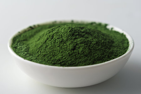 Vibrant green powder in a white ceramic bowl on a light background. Close-up shot highlighting the...