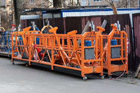 Multiple suspended scaffold platforms stand on site, showcasing industrial construction equipment...