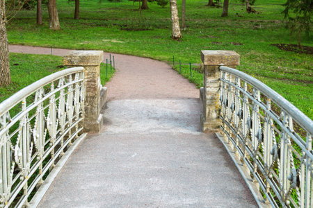 Close-up view of decorative iron bridge railings and stone pillars at park entrance, blending historical detail with natural surroundings.の写真素材