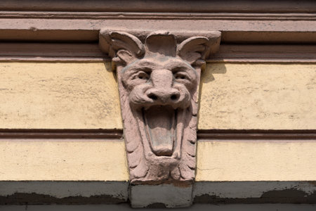 Ancient stone grotesque with open mouth decorates a historic building, evoking a sense of mystery and classical architectural heritage.の写真素材