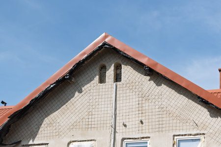 Renovation of a house facade with visible reinforcement mesh, unfinished windows, and a red gable...