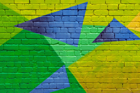 Vivid geometric street art mural with green, yellow, and blue triangles painted on brick wall brings energetic, urban style to modern backgrounds.の写真素材