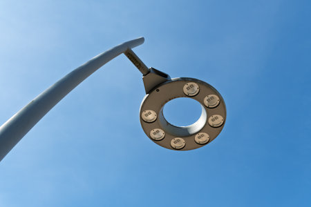 Modern circular street lamp with eight LED lights forms a futuristic silhouette against clear blue sky, evoking urban innovation and design.の写真素材