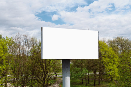 Large bill blankboard stands against a backdrop of green trees and blue sky, offering ideal space for outdoor advertising or announcements.の写真素材