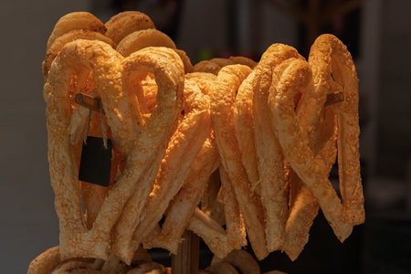Golden crispy pretzels stacked on wooden sticks under warm light, creating an inviting bakery scene with a focus on texture and freshness.の写真素材