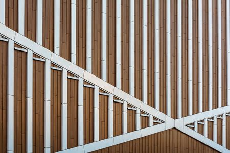 Modern building facade with geometric metal and wood panels forms dynamic pattern, emphasizing urban...