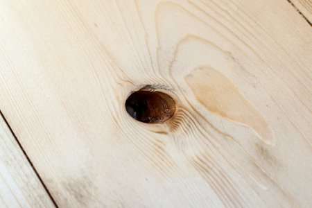 Close-up of a missing knot hole in wooden flooring highlights a common defect that must be repaired before applying varnish or any surface finish.の写真素材