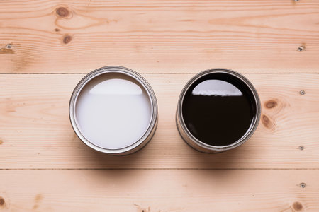 Two open cans with different wood coatings, light and dark, stand side by side on wooden floor, symbolizing the choice of finish for renovation.の写真素材