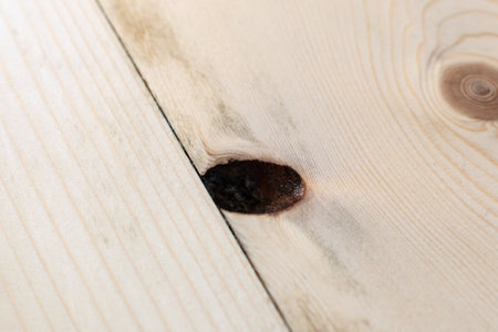 Macro shot of an elongated knot hole on a wooden plank reveals a typical issue found in natural wood floors, requiring repair for a smooth finish.の写真素材