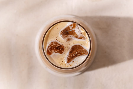 Chilled autumn latte with creamy foam and ice cubes creates a refreshing mood, evoking the comfort...