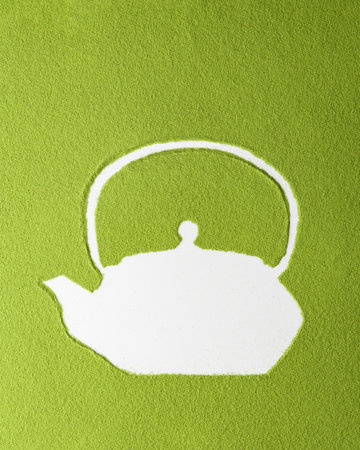 Bold matcha mockup with white teapot silhouette on green powder surface, high contrast composition suited for visuals.の写真素材