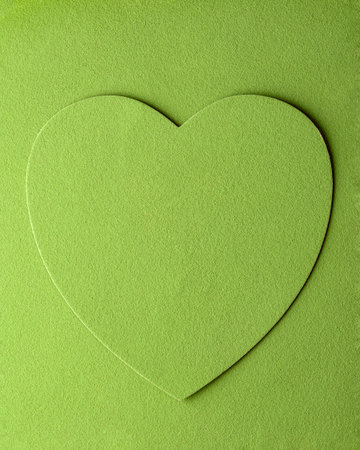 Heart shape stands out on vibrant green background, symbolizing love, care, and wellness in a minimalistic style.の写真素材