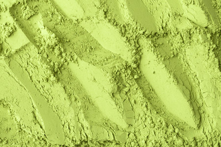 Fine matcha green tea powder creates abstract textured pattern with soft shadows, evoking natural organic surface for versatile design use.の写真素材