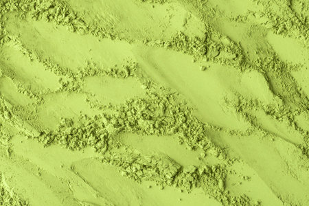 Diagonal streaks of vibrant matcha powder with crumbs create lively texture for ads and backgroundsの写真素材