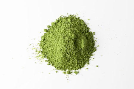 Bright green matcha powder forms a small mound on clean white background, creating contrast and highlighting organic texture.の写真素材