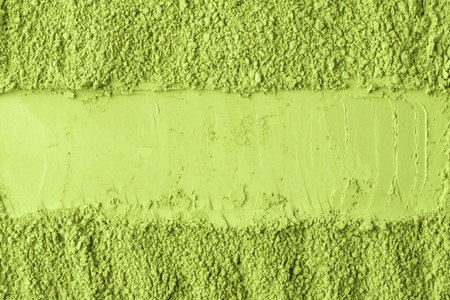 Green matcha powder is smoothed with a horizontal stripe, creating a mockup background for design,...