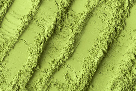 Soft matcha powder shaped into smooth curved lines, showing contrast between fluffy texture and compact surface areas.の写真素材