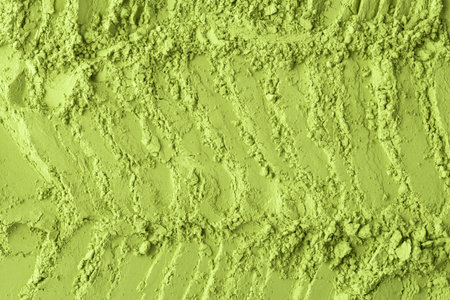 Loose matcha powder arranged in wavy textured lines provides a vivid, fresh background for creative culinary, health, and beauty content.の写真素材