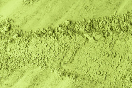 Fine green tea powder with visible layering and ridges forms a rustic natural surface for design use.の写真素材