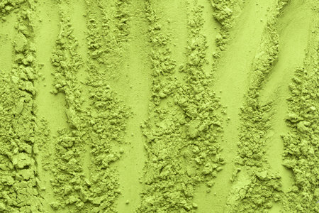 Vertical lines and clusters of matcha tea powder create a structured yet organic surface, ideal for modern food and wellness visual concepts.の写真素材