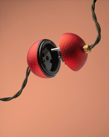 Bauble shaped like plug and socket hovers on twisted green cord, hinting at festive glow and playful start of holiday season.の写真素材