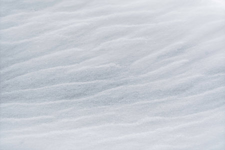 Soft rippled snow surface forming gentle natural texture under diffused winter light creates calm minimal background for seasonal designs.の写真素材